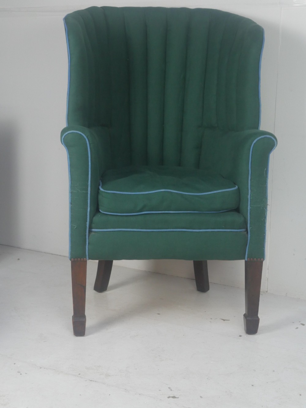 A forest green upholstered barrel back armchair with vertical channel tufting, light blue contrast piping, and dark tapered square legs. View XIII
