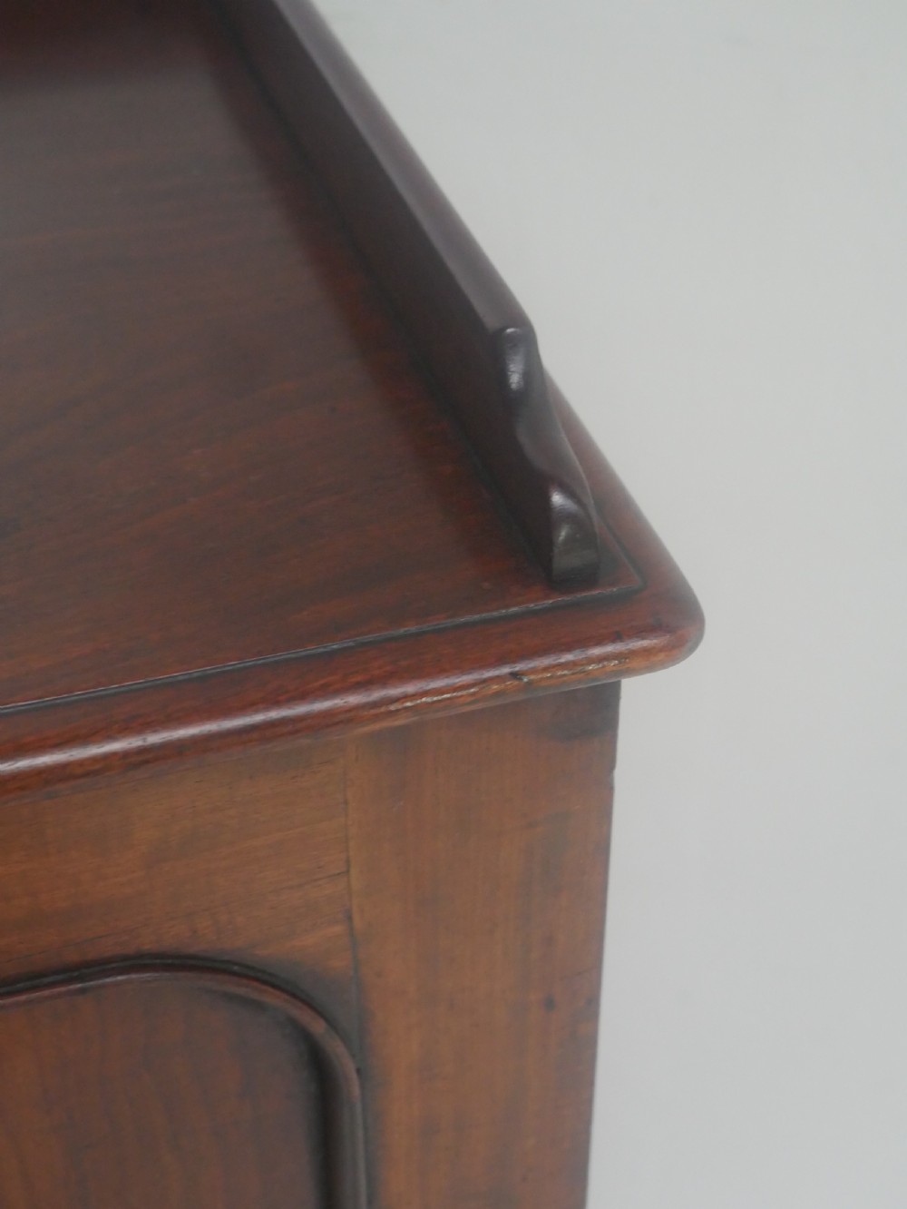 A 19th-century mahogany bedside cupboard featuring a single arched panel door, turned wooden knob, top galley edge, and a solid plinth base. View VIII