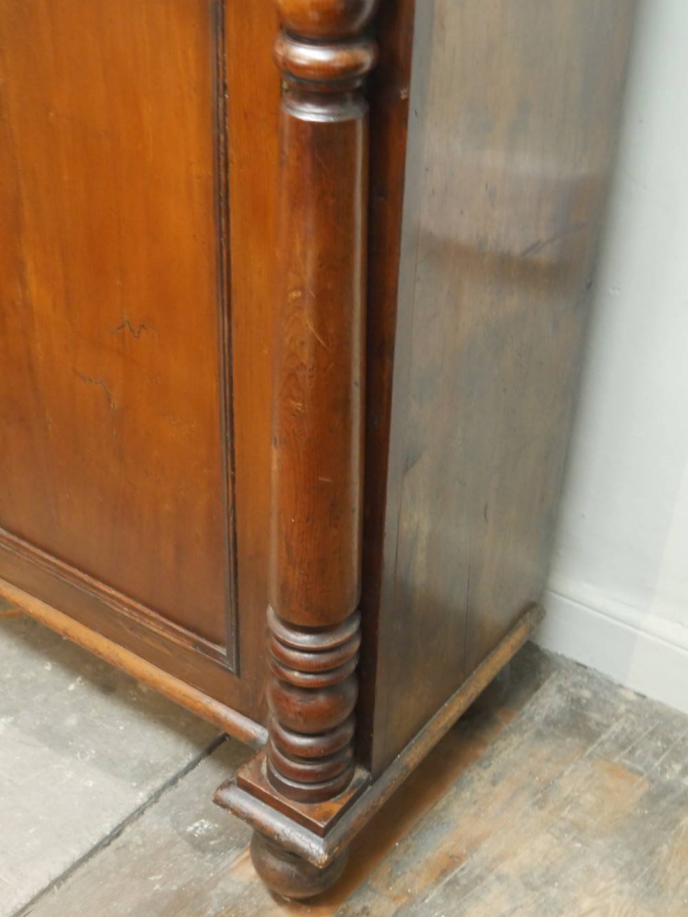 A warm brown cedar cupboard featuring two top drawers, twin panelled doors, and carved side columns supported by turned feet. View IV