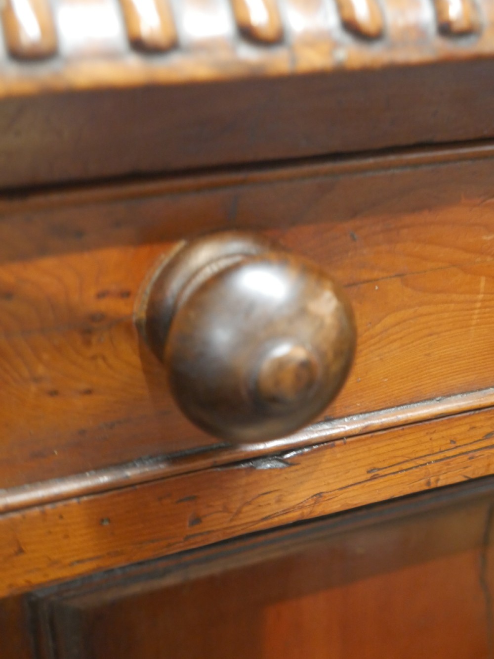 A warm brown cedar cupboard featuring two top drawers, twin panelled doors, and carved side columns supported by turned feet. View IX