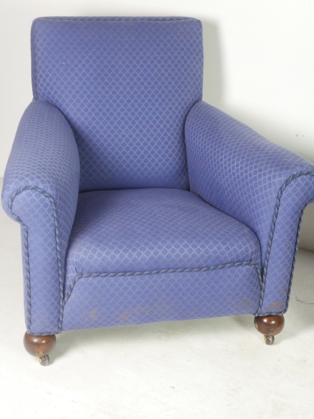 A pair of high-backed armchairs upholstered in patterned blue fabric with rolled arms and turned wooden feet on brass castors. View III