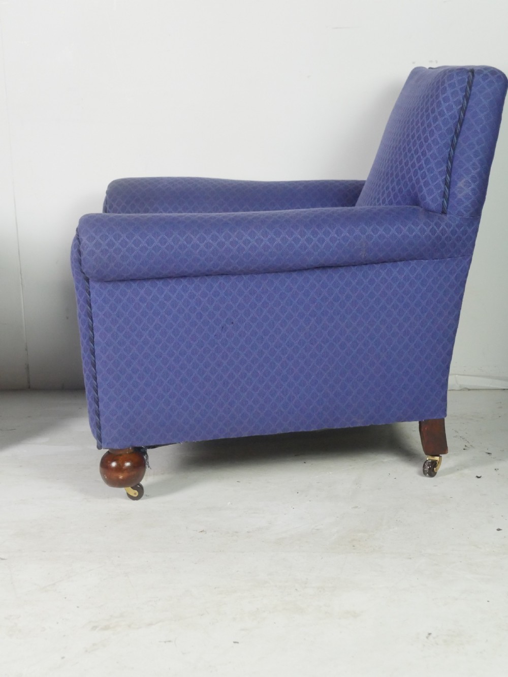 A pair of high-backed armchairs upholstered in patterned blue fabric with rolled arms and turned wooden feet on brass castors. View IV