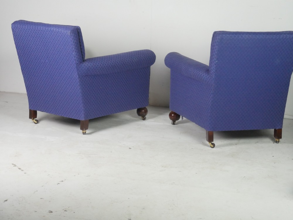 A pair of high-backed armchairs upholstered in patterned blue fabric with rolled arms and turned wooden feet on brass castors. View VIII