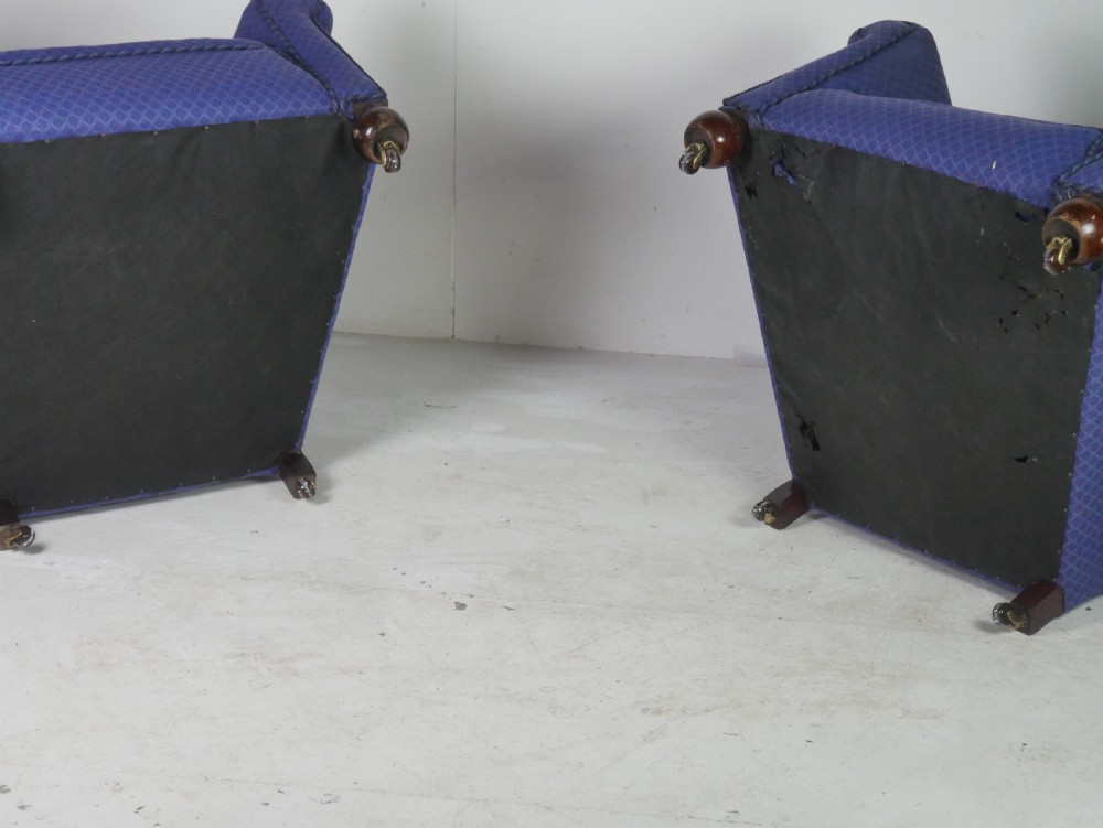 A pair of high-backed armchairs upholstered in patterned blue fabric with rolled arms and turned wooden feet on brass castors. View IX