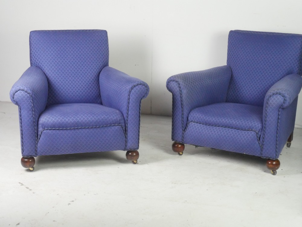 A pair of high-backed armchairs upholstered in patterned blue fabric with rolled arms and turned wooden feet on brass castors. View XII