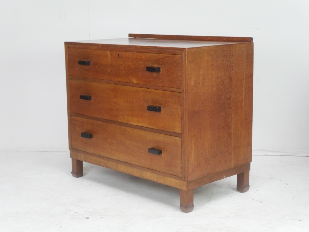 A mid-20th-century golden oak chest of drawers featuring three full-width drawers with contrasting dark wooden block handles and a low rear gallery rail. View III