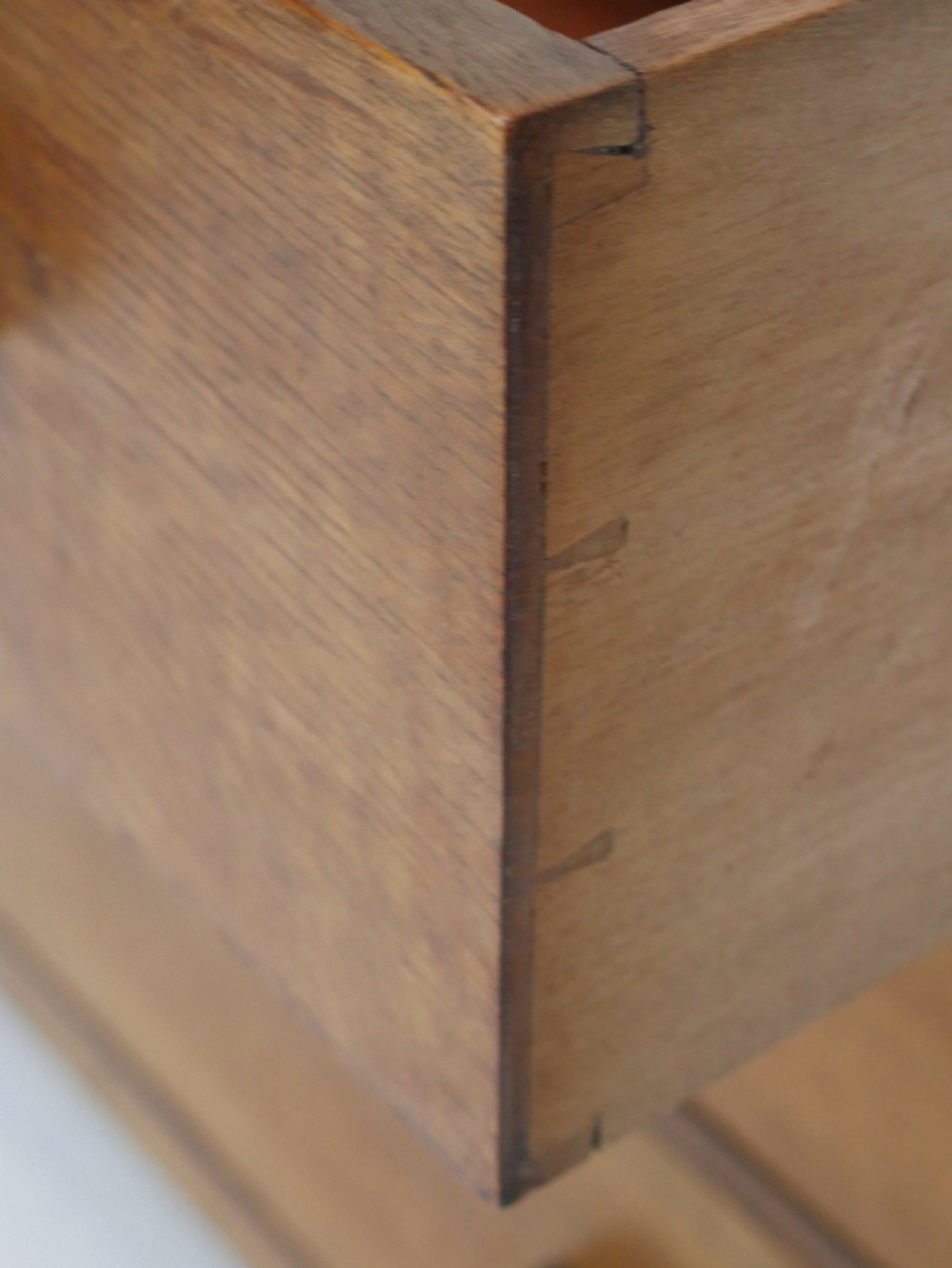 A mid-20th-century golden oak chest of drawers featuring three full-width drawers with contrasting dark wooden block handles and a low rear gallery rail. View VII