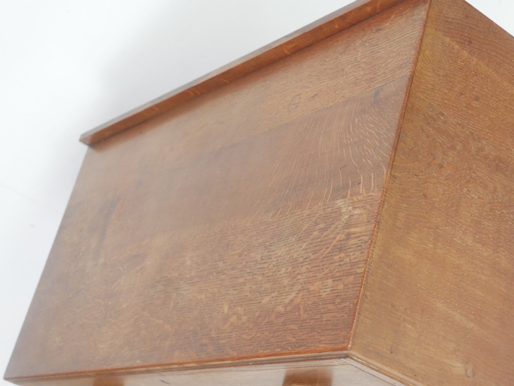 A mid-20th-century golden oak chest of drawers featuring three full-width drawers with contrasting dark wooden block handles and a low rear gallery rail. View IX