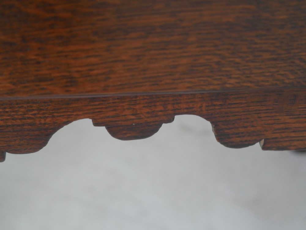 An antique dark oak side table featuring a single drawer with pierced brass handles, a shaped apron, and tapered legs ending in pad feet. View II