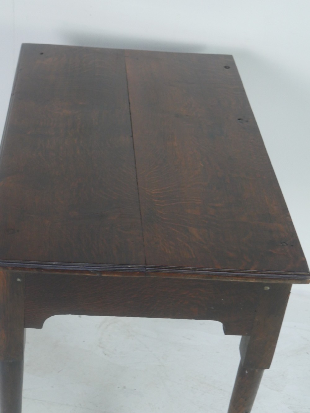 An antique dark oak side table featuring a single drawer with pierced brass handles, a shaped apron, and tapered legs ending in pad feet. View V