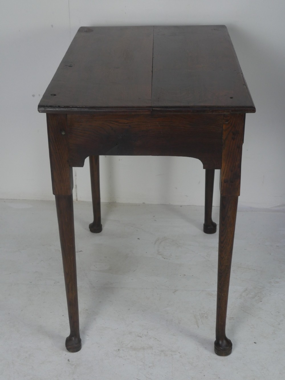 An antique dark oak side table featuring a single drawer with pierced brass handles, a shaped apron, and tapered legs ending in pad feet. View VIII
