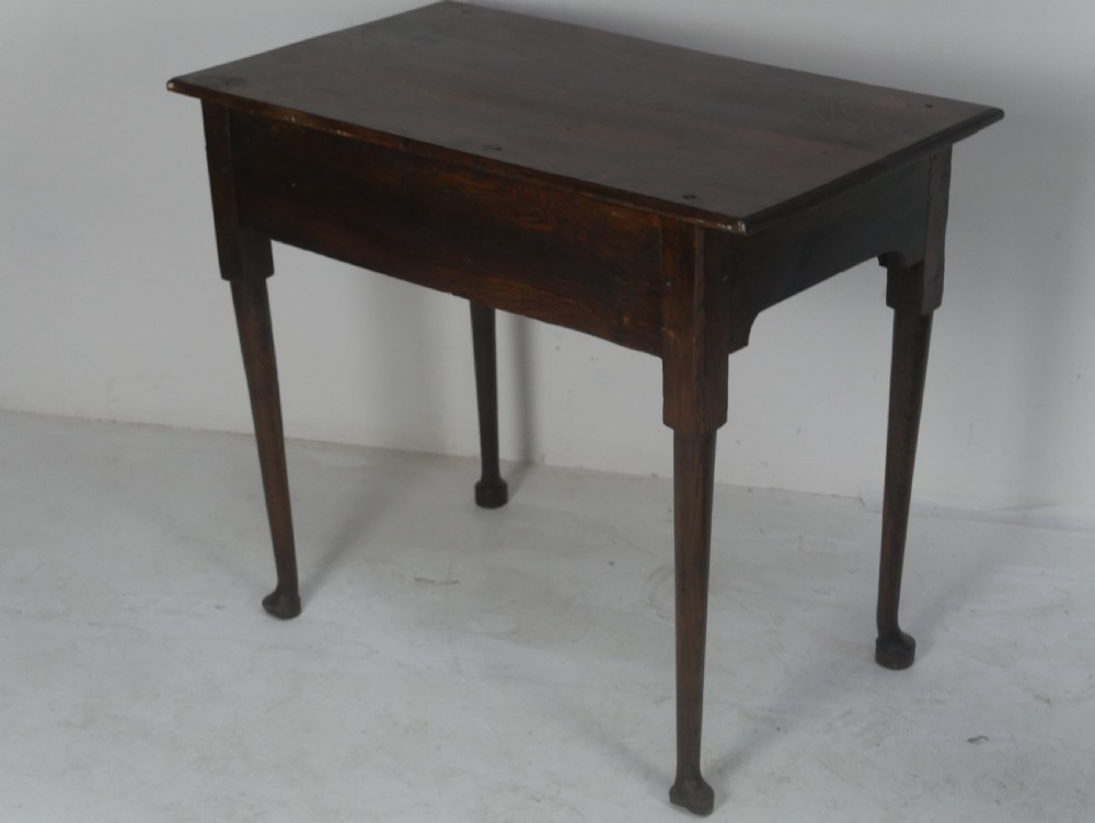 An antique dark oak side table featuring a single drawer with pierced brass handles, a shaped apron, and tapered legs ending in pad feet. View IX