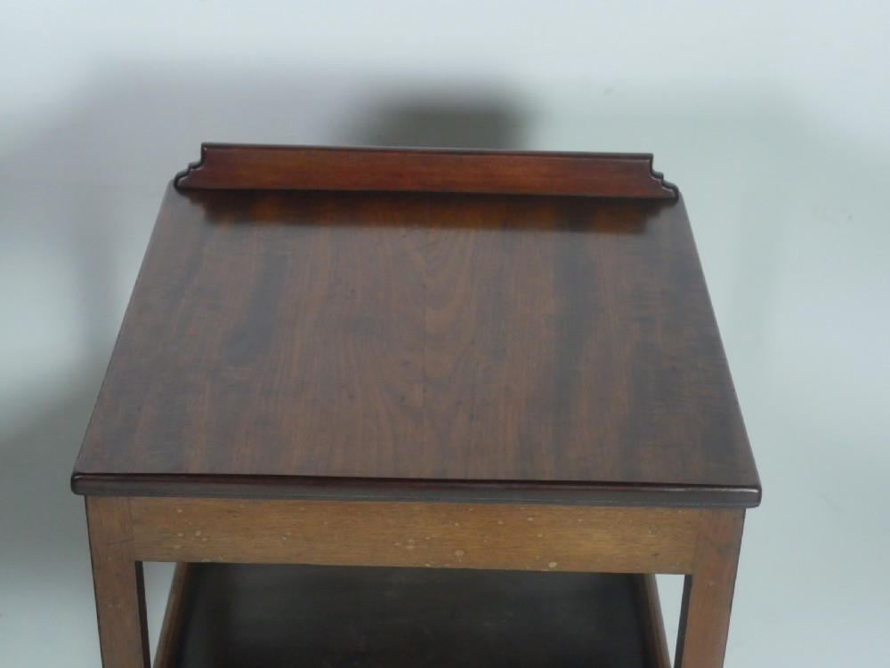 A narrow dark mahogany bedside table featuring a top surface with a gallery back, an open central shelf, a single drawer with a brass drop handle, and cross stretchers with a turned dish centre. View II