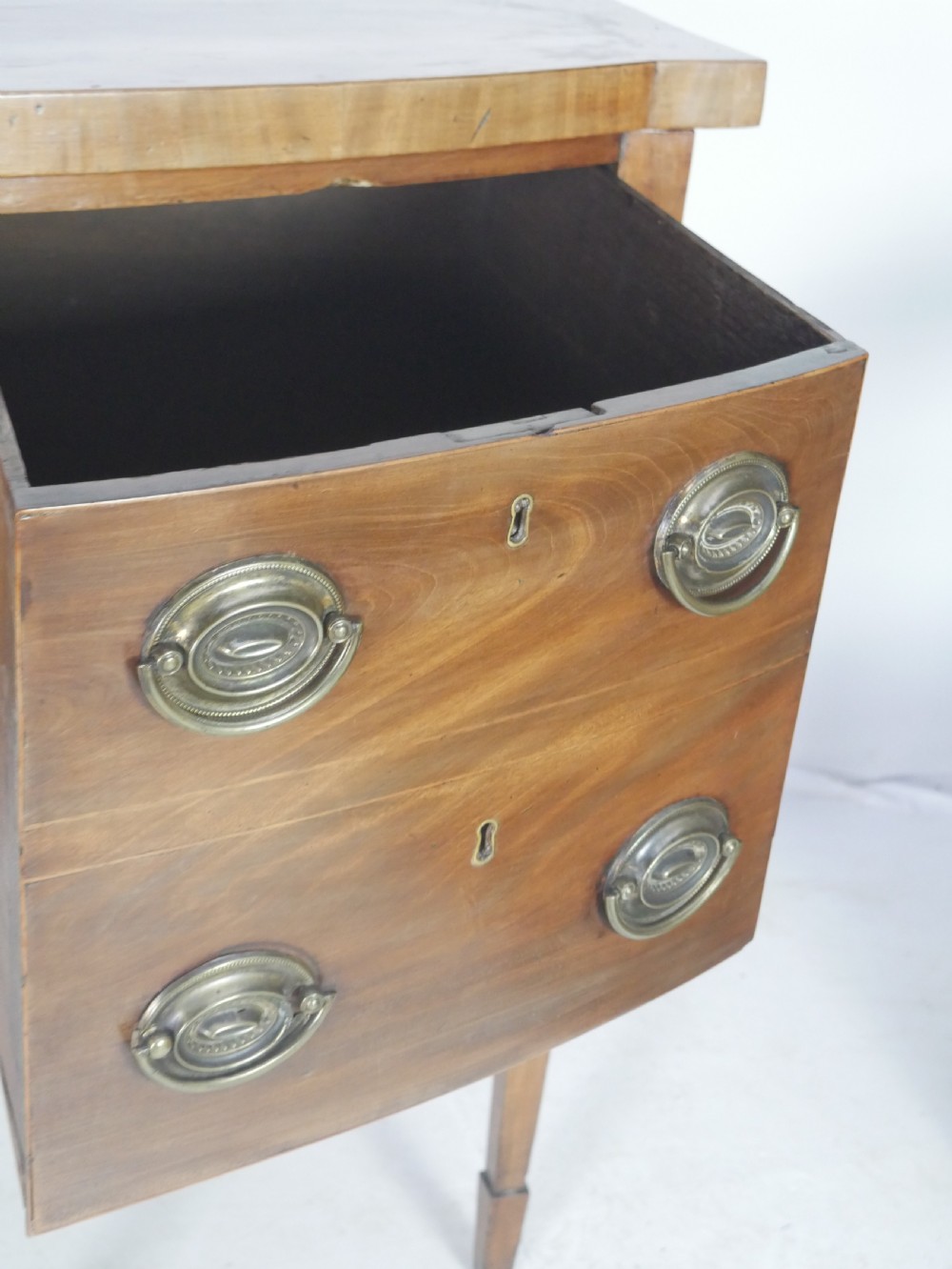 A Georgian mahogany bow-front sideboard featuring a central arch aperture, multiple drawers with oval brass handles, and square tapered legs. View VII