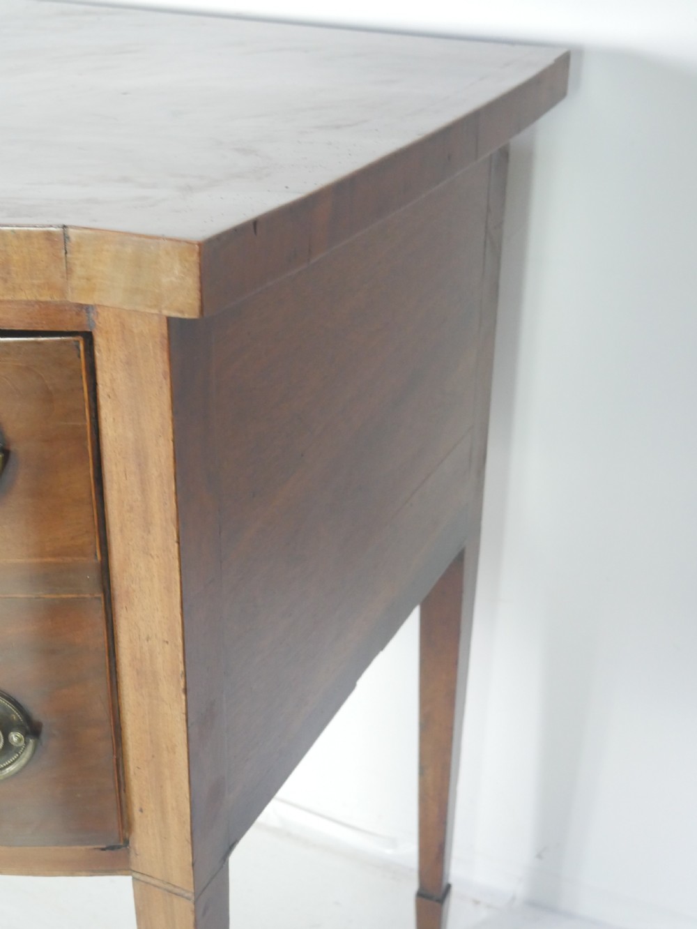 A Georgian mahogany bow-front sideboard featuring a central arch aperture, multiple drawers with oval brass handles, and square tapered legs. View IX