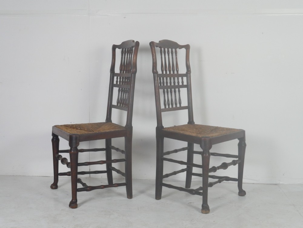 A pair of Georgian brown elm side chairs featuring spindle backrests, woven rush seats, and turned front legs. View II