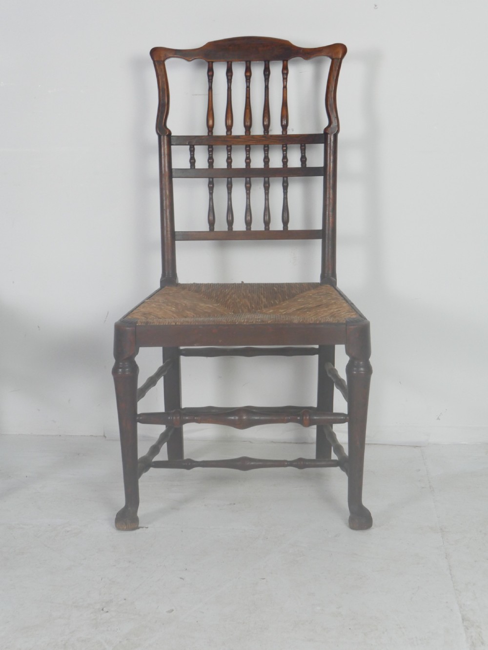 A pair of Georgian brown elm side chairs featuring spindle backrests, woven rush seats, and turned front legs. View IV