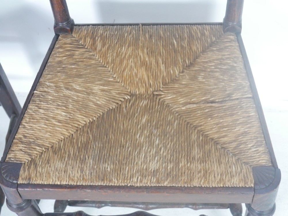 A pair of Georgian brown elm side chairs featuring spindle backrests, woven rush seats, and turned front legs. View X