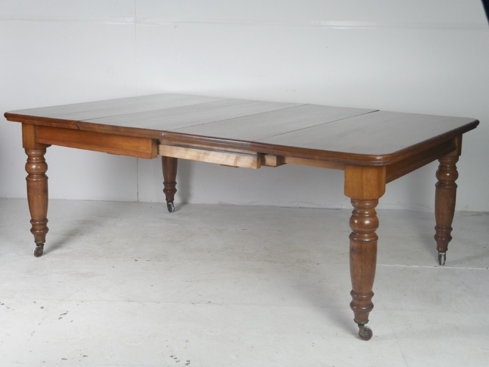 Victorian mahogany extending dining table resting on four turned legs with metal castors.