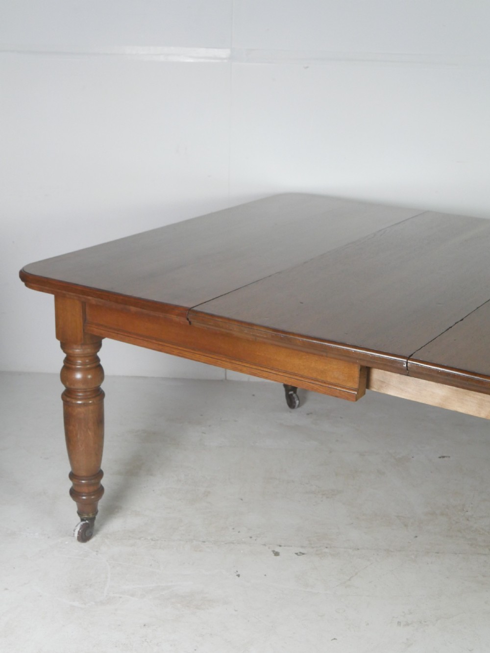 Victorian mahogany extending dining table resting on four turned legs with metal castors. View III