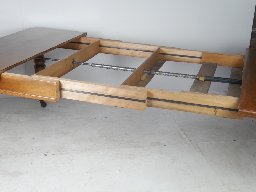 Victorian mahogany extending dining table resting on four turned legs with metal castors. View VI