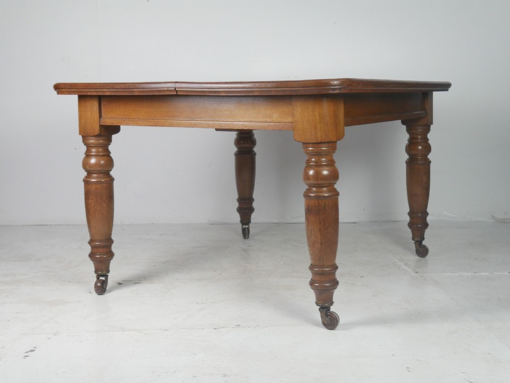 Victorian mahogany extending dining table resting on four turned legs with metal castors. View VIII