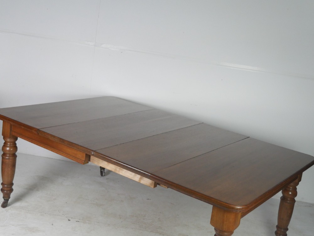 Victorian mahogany extending dining table resting on four turned legs with metal castors. View IX