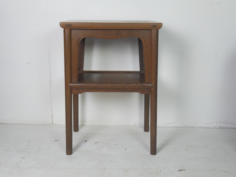 A warm brown oak side table featuring an upper rectangular top, arched aprons, a lower storage shelf, and straight legs. View X