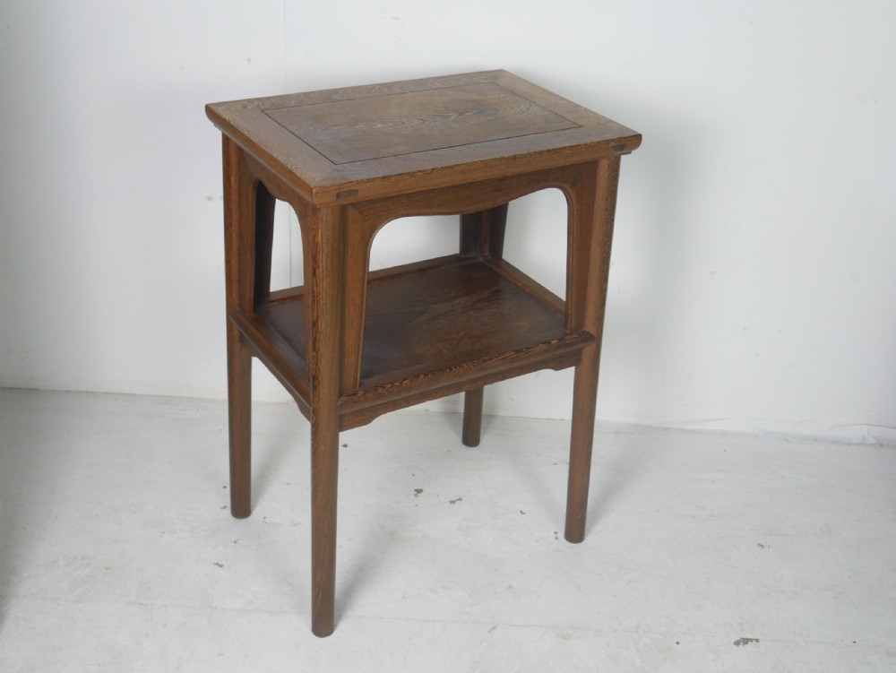A warm brown oak side table featuring an upper rectangular top, arched aprons, a lower storage shelf, and straight legs. View XI