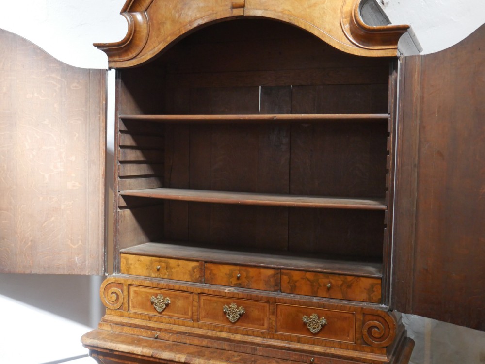 An 18th-century Dutch Rococo burr walnut cabinet featuring an arched moulded cornice, panelled doors, and a bombe three-drawer base with brass hardware. View III