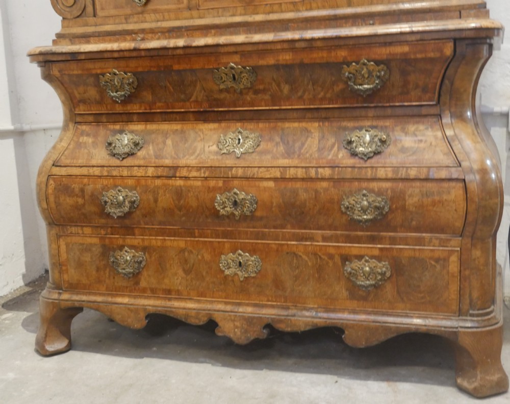 An 18th-century Dutch Rococo burr walnut cabinet featuring an arched moulded cornice, panelled doors, and a bombe three-drawer base with brass hardware. View IV