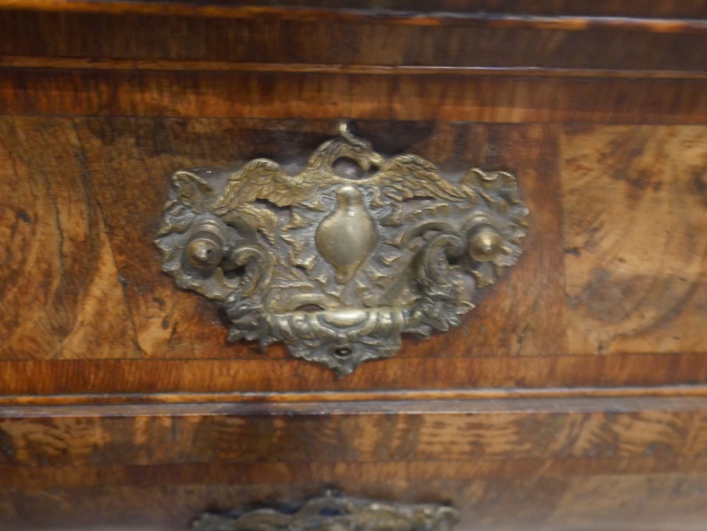 An 18th-century Dutch Rococo burr walnut cabinet featuring an arched moulded cornice, panelled doors, and a bombe three-drawer base with brass hardware. View IX