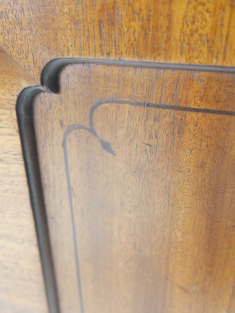 An antique mahogany kneehole dressing table featuring flame veneer drawer fronts, panelled cupboard doors, and turned feet. View X