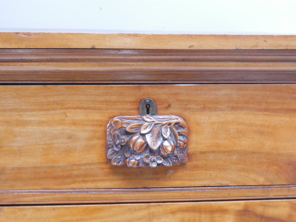 A 19th-century warm brown wooden tallboy chest featuring two short drawers over three long drawers with intricate carved foliate handles. View II