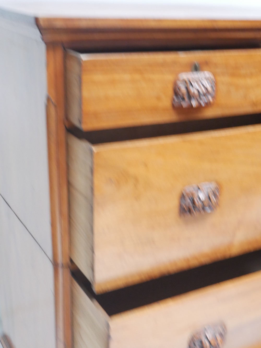 A 19th-century warm brown wooden tallboy chest featuring two short drawers over three long drawers with intricate carved foliate handles. View III