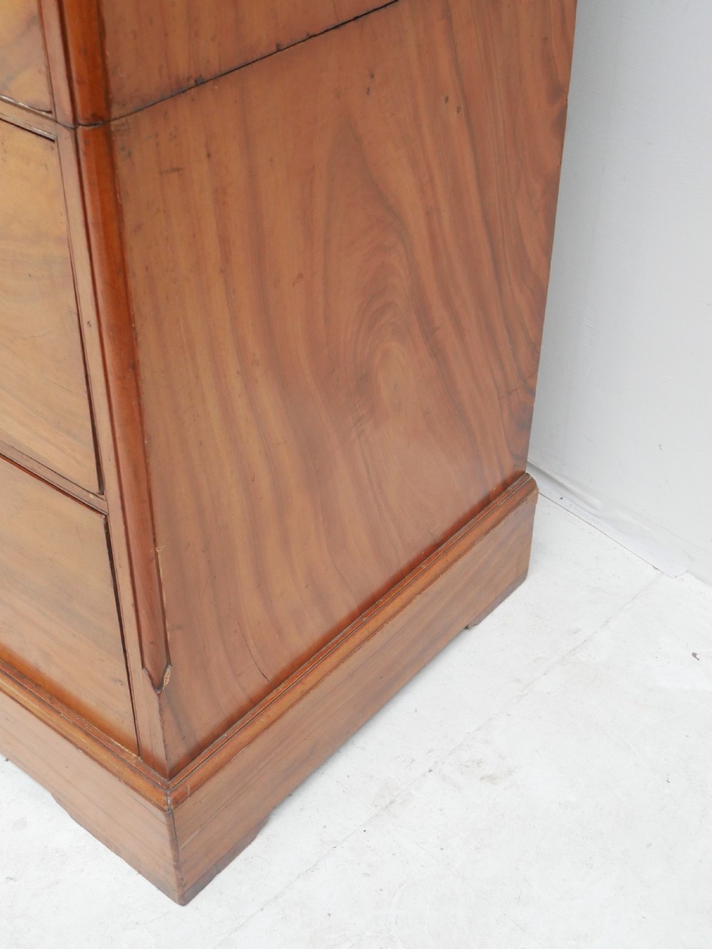 A 19th-century warm brown wooden tallboy chest featuring two short drawers over three long drawers with intricate carved foliate handles. View VII