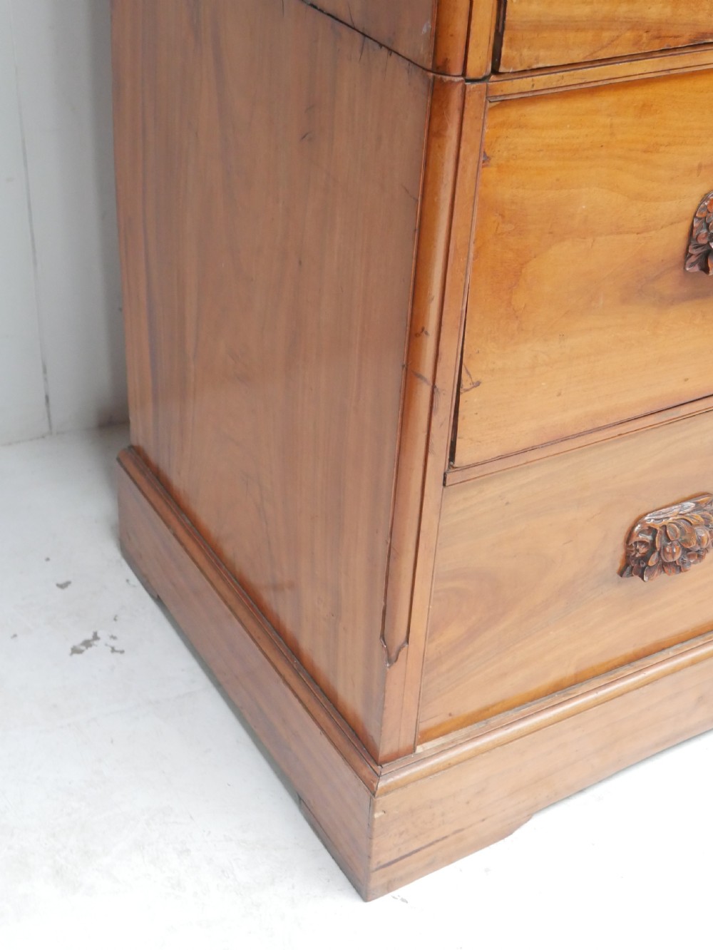 A 19th-century warm brown wooden tallboy chest featuring two short drawers over three long drawers with intricate carved foliate handles. View IX