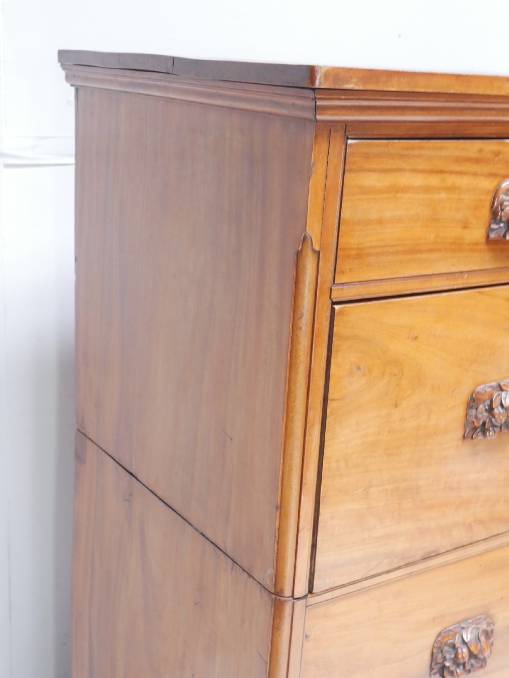 A 19th-century warm brown wooden tallboy chest featuring two short drawers over three long drawers with intricate carved foliate handles. View X