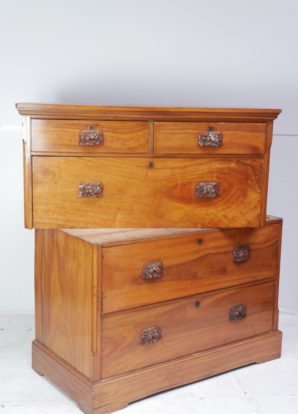 A 19th-century warm brown wooden tallboy chest featuring two short drawers over three long drawers with intricate carved foliate handles. View V