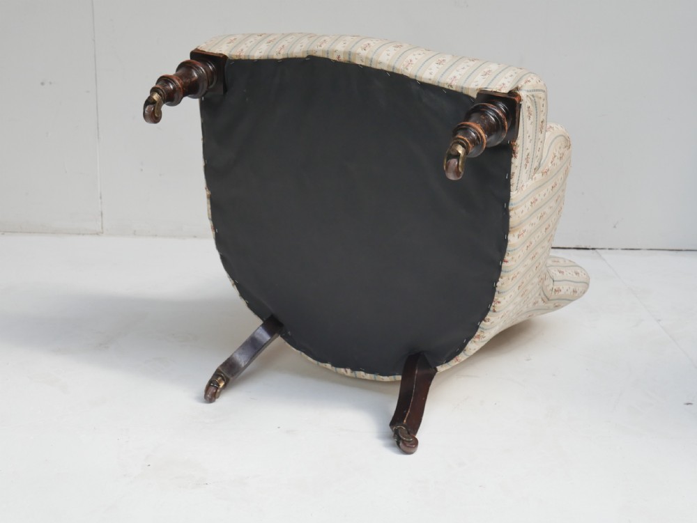 A low Victorian button-backed armchair upholstered in beige floral striped fabric with turned mahogany front legs on castors. View VIII