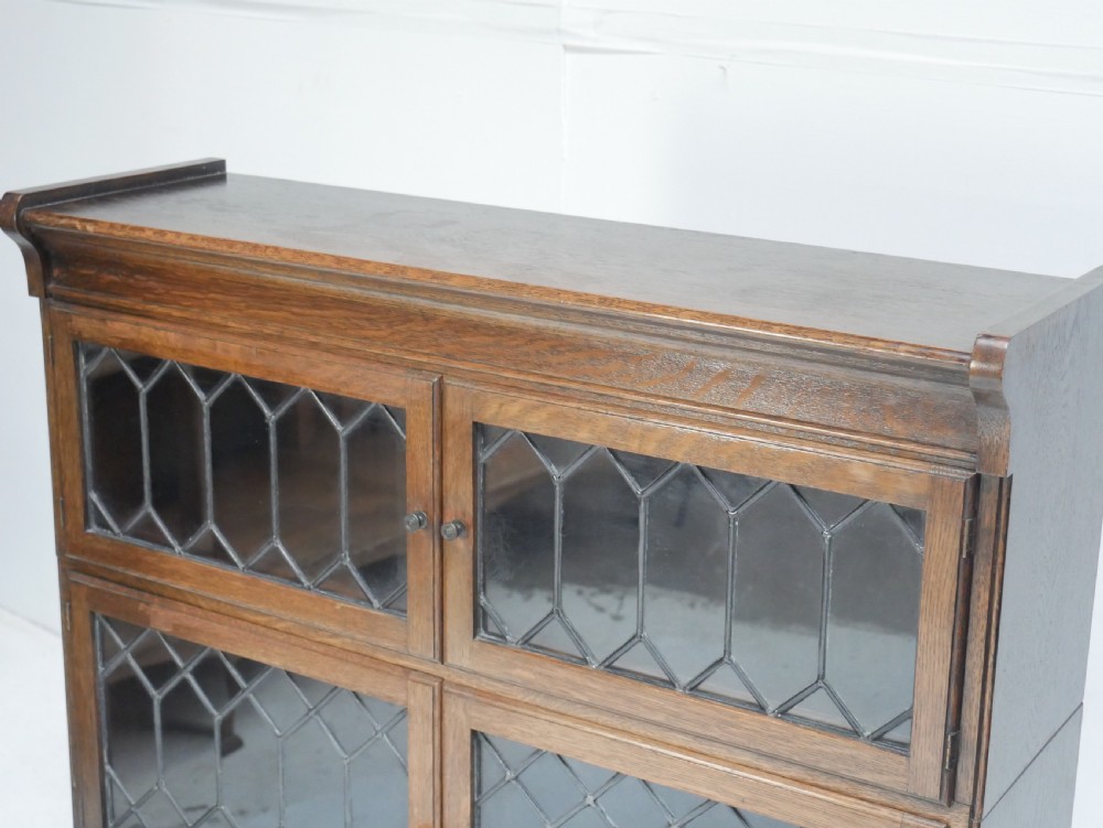 An oak stacking bookcase featuring two upper tiers with double diamond-pattern leaded glass doors above a lower cupboard with two solid panelled wooden doors. View IV