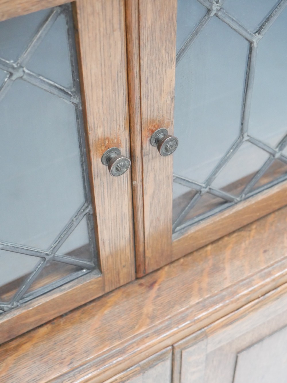An oak stacking bookcase featuring two upper tiers with double diamond-pattern leaded glass doors above a lower cupboard with two solid panelled wooden doors. View VII