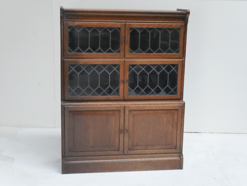 An oak stacking bookcase featuring two upper tiers with double diamond-pattern leaded glass doors above a lower cupboard with two solid panelled wooden doors. View XI