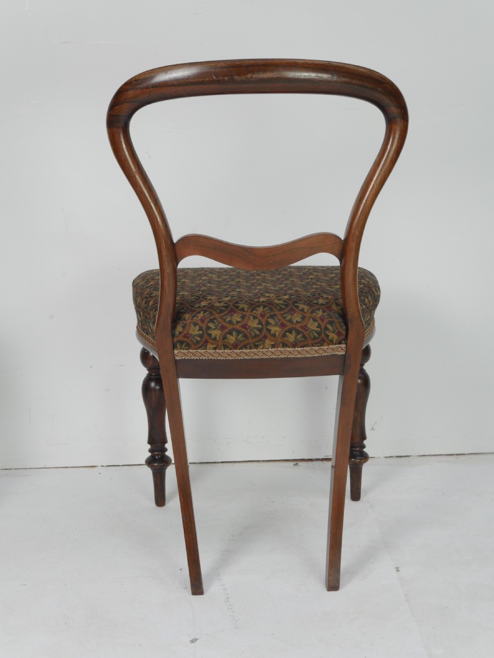 A pair of Victorian rosewood balloon back side chairs featuring turned front legs and patterned upholstered seats. View III