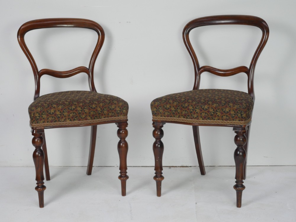 A pair of Victorian rosewood balloon back side chairs featuring turned front legs and patterned upholstered seats. View X
