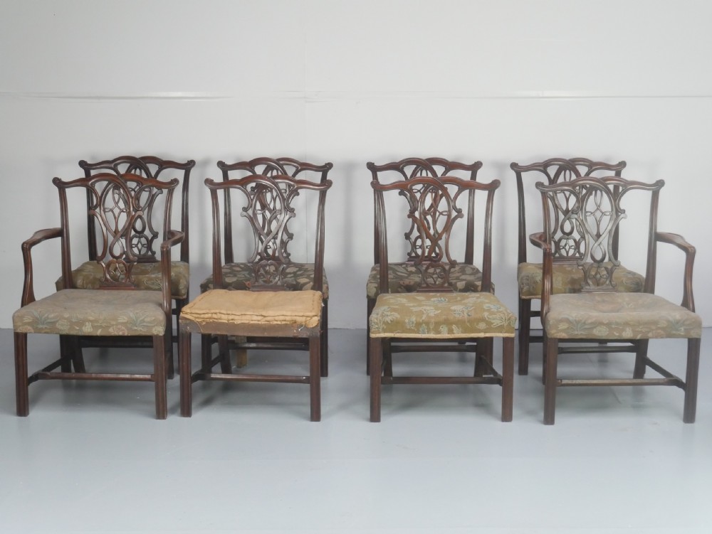 A set of eight dark mahogany Georgian style dining chairs featuring carved pierced splats and patterned fabric drop-in seats, comprising six side chairs and two carver armchairs.