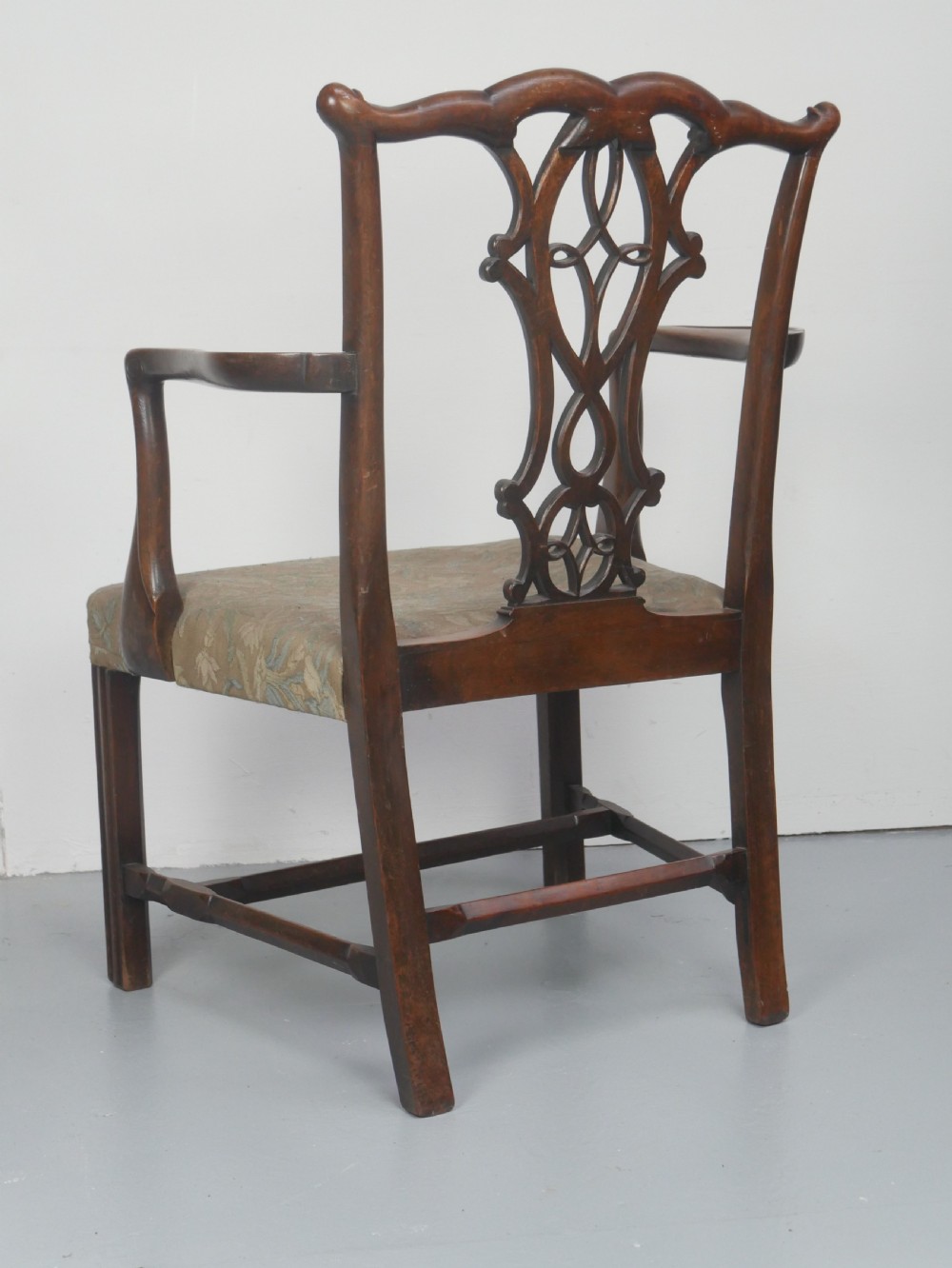 A set of eight dark mahogany Georgian style dining chairs featuring carved pierced splats and patterned fabric drop-in seats, comprising six side chairs and two carver armchairs. View XVI