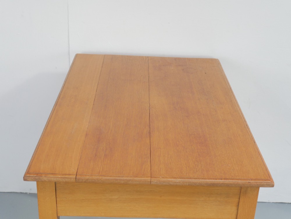 A golden oak writing table with two frieze drawers fitted with brass drop handles, raised on four square tapered legs. View X