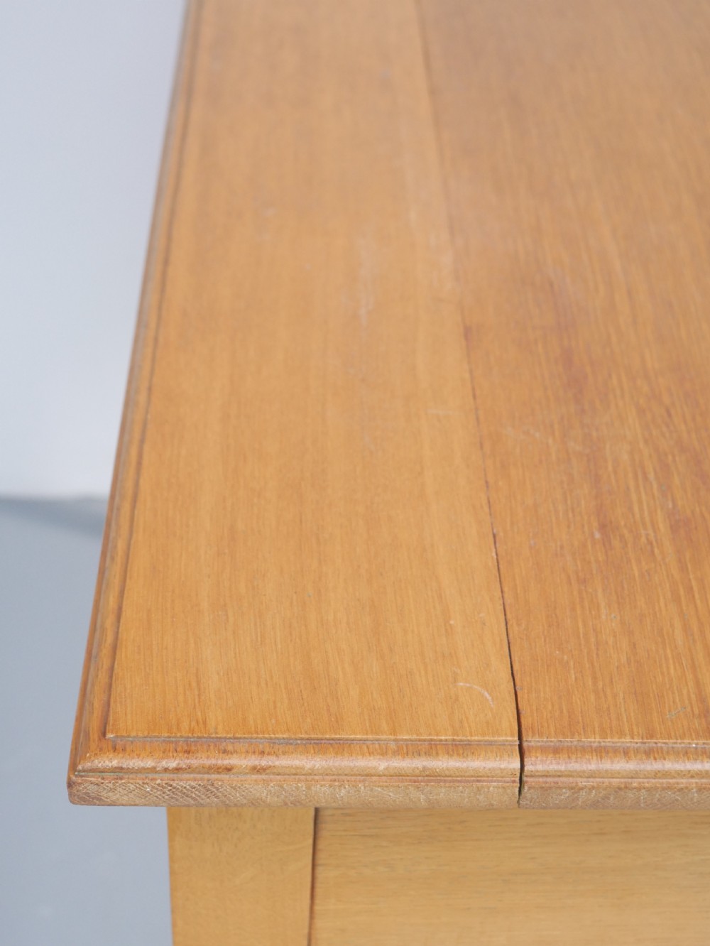 A golden oak writing table with two frieze drawers fitted with brass drop handles, raised on four square tapered legs. View XII