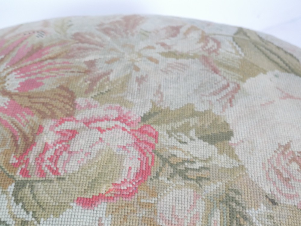 An oval upholstered stool featuring dark carved wooden cabriole legs with castors and a floral needlepoint fabric top. View III